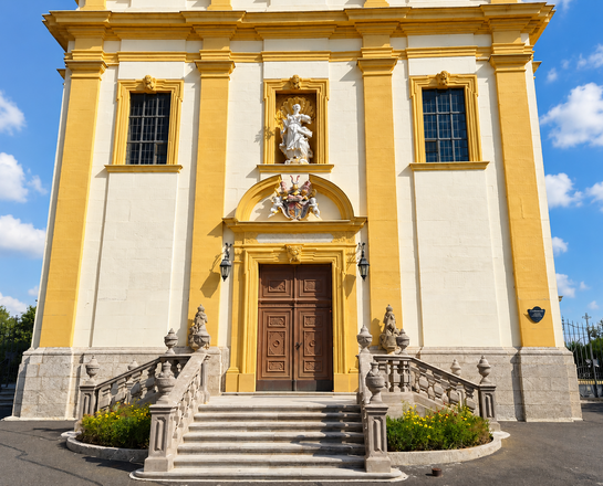 Heilige Schutzengel und St. Jakobus der Ältere (Gaukönigshofen) Das Bild zeigt die barocke Kirchenfassade der Schutzengelkirche in Gaukönigshofen mit breiter Steintreppe und großem braunen Eingangsportal.